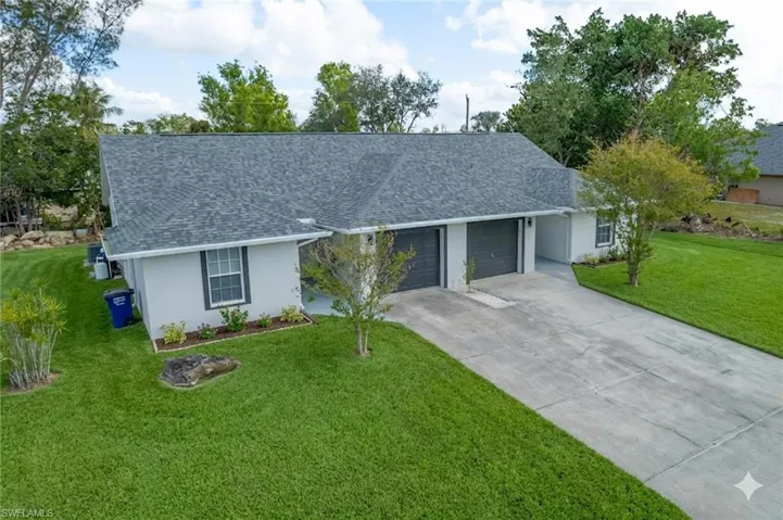 Single story home featuring a front lawn, a shingled roof, a garage, and stucco siding