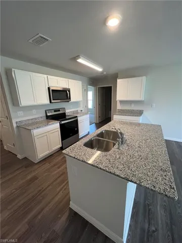 Kitchen with appliances with stainless steel finishes, a sink, white cabinetry, and visible vents