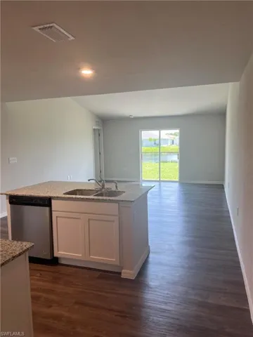 Kitchen with dark wood finished floors, visible vents, dishwasher, a sink, and open floor plan