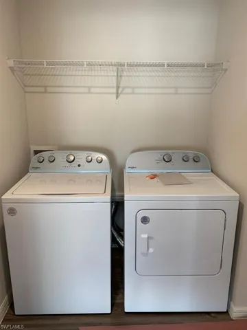 Clothes washing area featuring baseboards, washer and dryer, laundry area, and dark wood-style floors