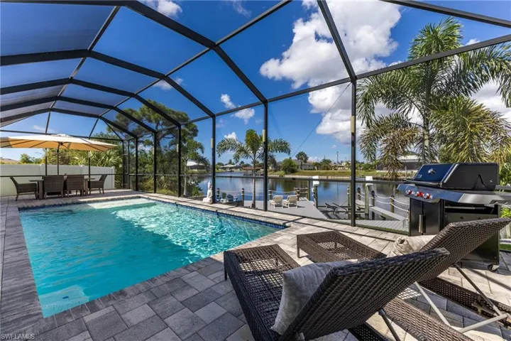 Swimming pool with a water view, glass enclosure, a sunroom, and a patio area