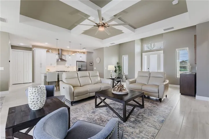 Living room with coffered ceiling, beamed ceiling, a ceiling fan, and light wood finished floors