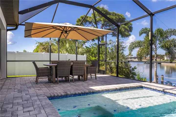 Outdoor pool featuring glass enclosure, a water view, a patio, and a sunroom