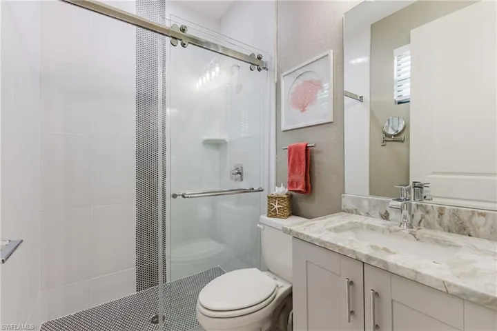 Full bath featuring vanity, a shower stall, and a textured wall
