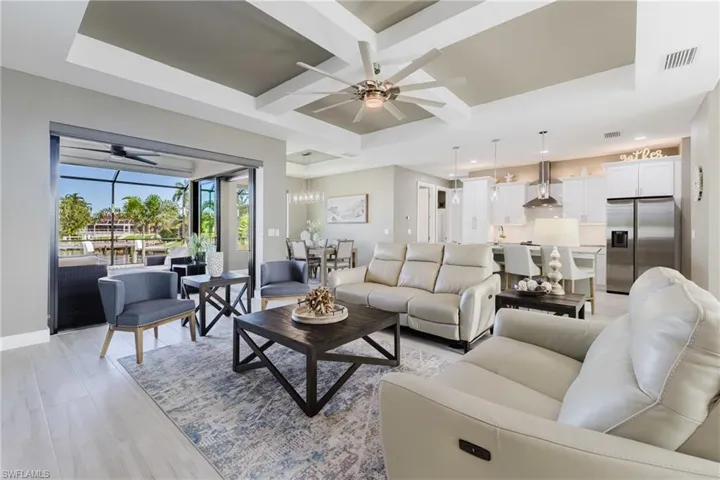 Living room featuring a ceiling fan, coffered ceiling, light wood finished floors, and beam ceiling