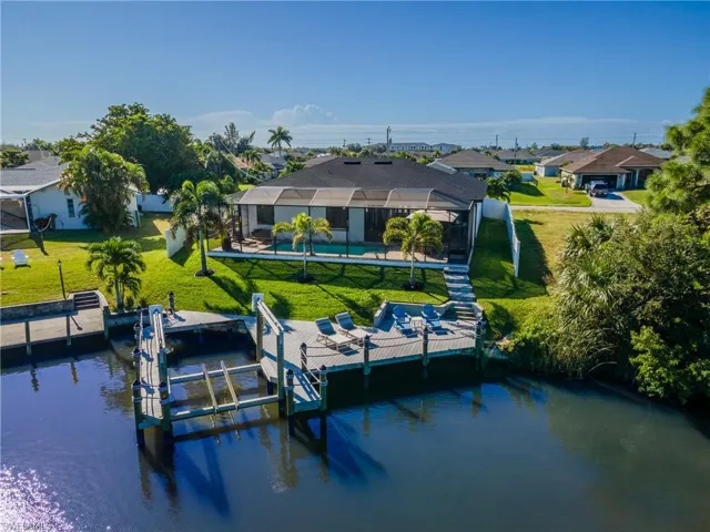 Dock with a lanai, boat lift, a lawn, a water view, and a sunroom