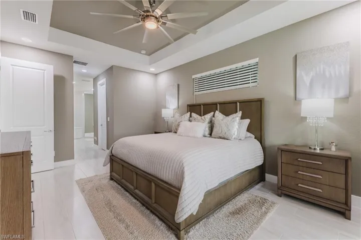 Bedroom with a ceiling fan, light wood-type flooring, recessed lighting, and a raised ceiling