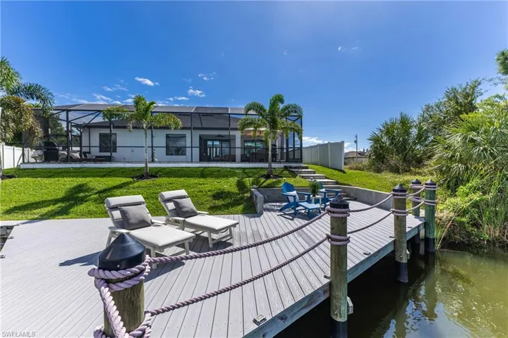 Dock area featuring a lanai, a lawn, a patio, a deck with water view, and a sunroom