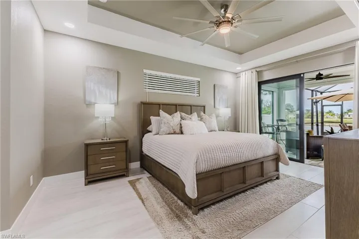 Bedroom featuring a tray ceiling, access to exterior, ceiling fan, and a sunroom