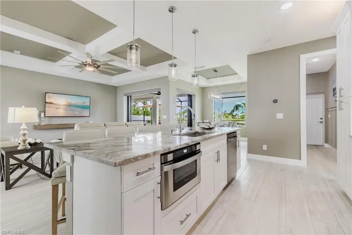 Kitchen featuring light stone counters, a kitchen bar, white cabinets, pendant lighting, and plenty of natural light