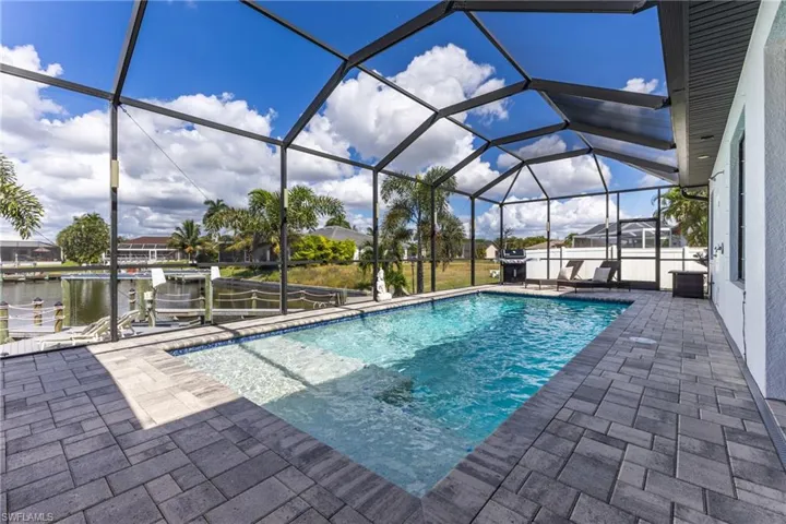 Swimming pool with a lanai, boat lift, a sunroom, a dock, and a patio