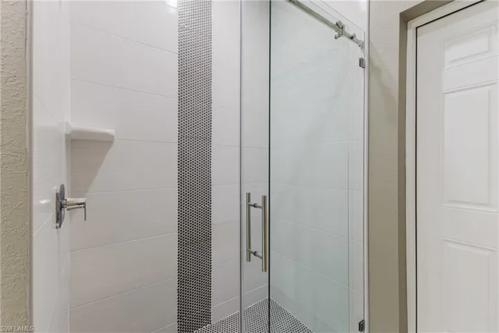Bathroom with a shower stall and a textured wall