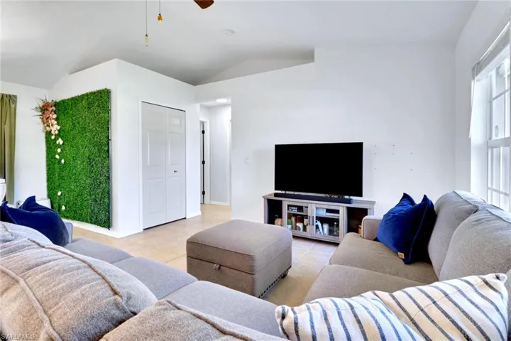 Living area with ceiling fan, lofted ceiling, and light tile patterned floors