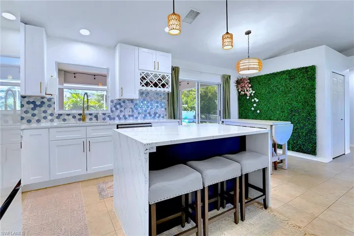 Kitchen featuring white cabinetry, tasteful backsplash, pendant lighting, light tile patterned floors, and light stone counters