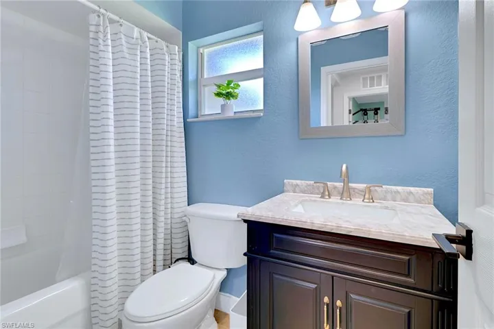 Full bathroom featuring shower / tub combo, a textured wall, and vanity