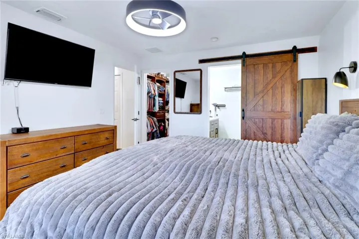 Bedroom featuring a barn door, a walk in closet, and ensuite bath