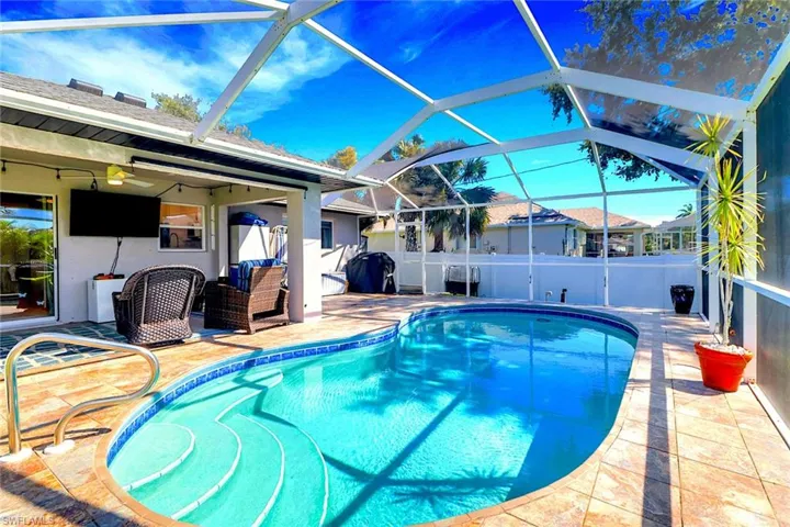 Outdoor pool with glass enclosure, a sunroom, and a patio