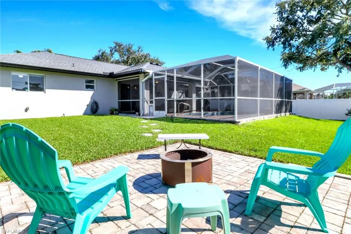 Rear view of house featuring a fire pit, a lanai, a patio, stucco siding, and a sunroom