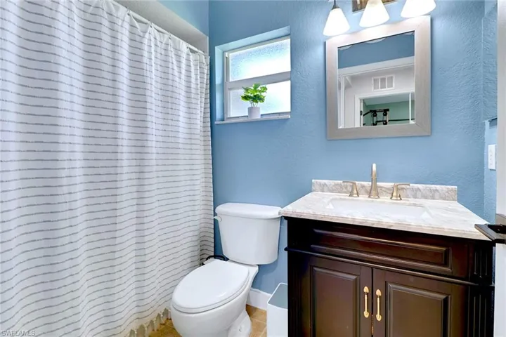 Full bath with a textured wall, vanity, and curtained shower