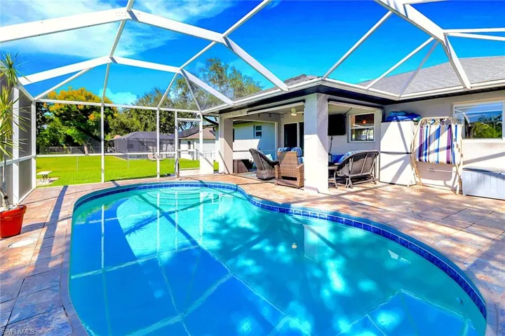 Swimming pool featuring a sunroom, glass enclosure, a patio, and an outdoor living space
