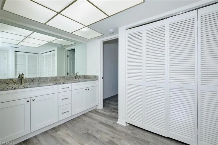 Bathroom featuring a double vanity with granite-style countertop, dual sinks, and under-sink cabinetry