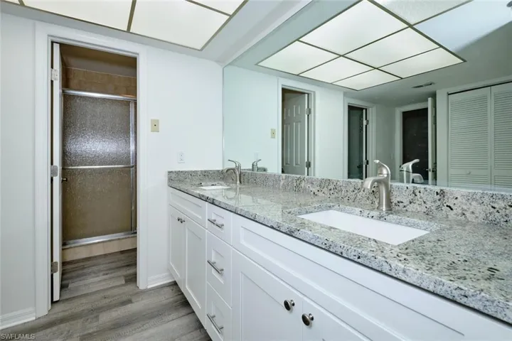 Bathroom featuring a dual vanity with white cabinetry, stone countertops, and undermount sinks