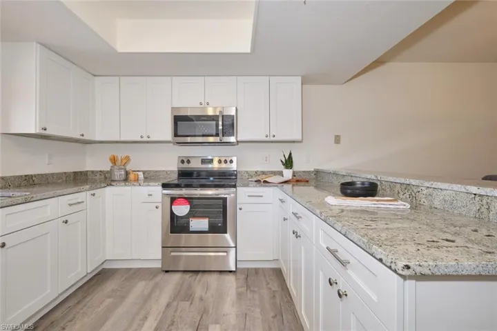 U-shaped kitchen featuring white cabinetry, stainless steel range and microwave