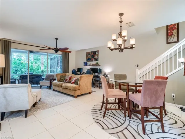Tiled dining space featuring ceiling fan with notable chandelier