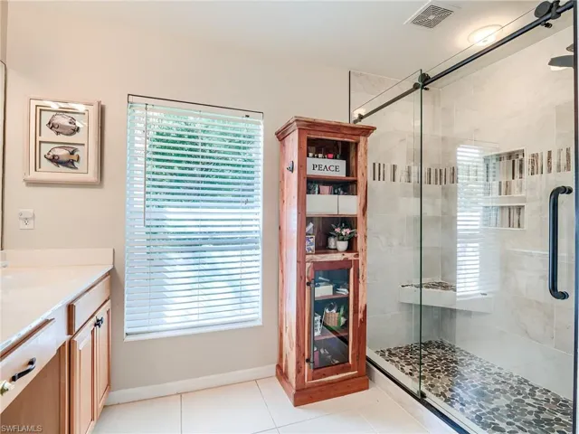 Bathroom featuring tile patterned floors, an enclosed shower, a wealth of natural light, and vanity