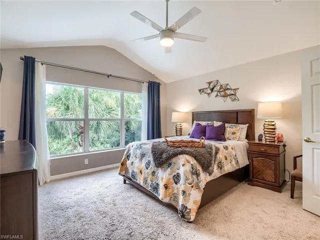 Carpeted bedroom featuring lofted ceiling and ceiling fan