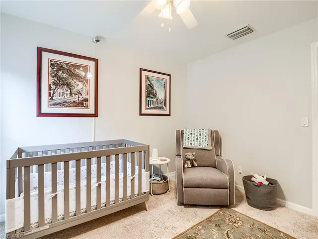 Carpeted bedroom with a nursery area and ceiling fan