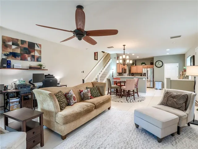 Tiled living room featuring ceiling fan with notable chandelier