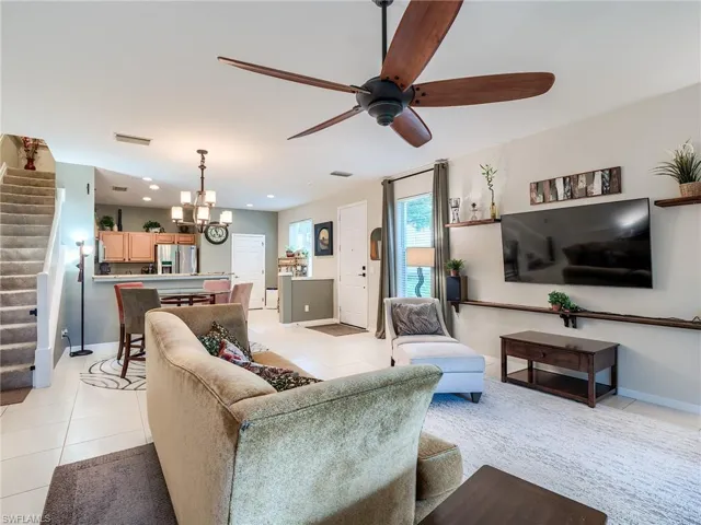 Living room featuring ceiling fan with notable chandelier and light tile patterned floors