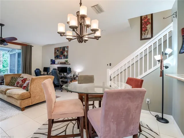 Dining area with light tile patterned flooring and ceiling fan with notable chandelier