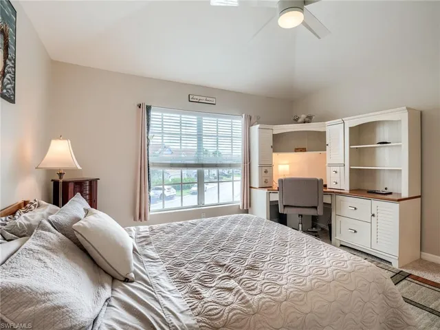 Carpeted bedroom featuring ceiling fan and vaulted ceiling