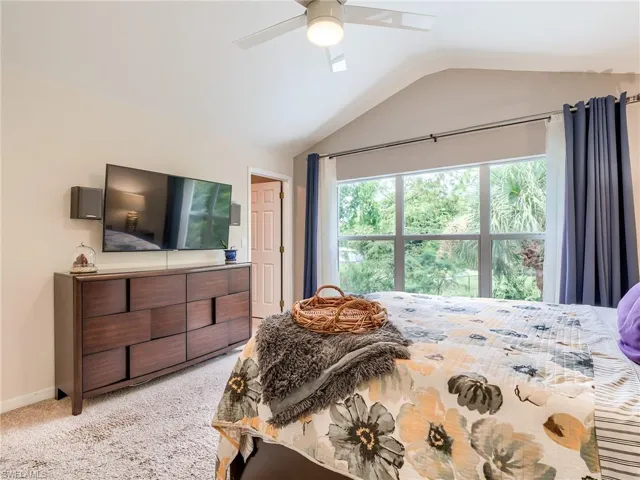 Carpeted bedroom with ceiling fan and vaulted ceiling