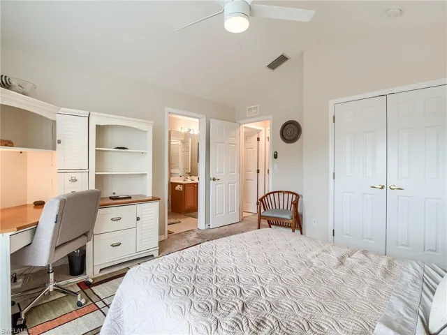Bedroom with light tile patterned flooring, ceiling fan, connected bathroom, and a closet