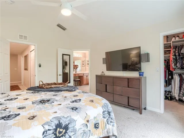 Bedroom featuring light carpet, a closet, ensuite bath, and ceiling fan