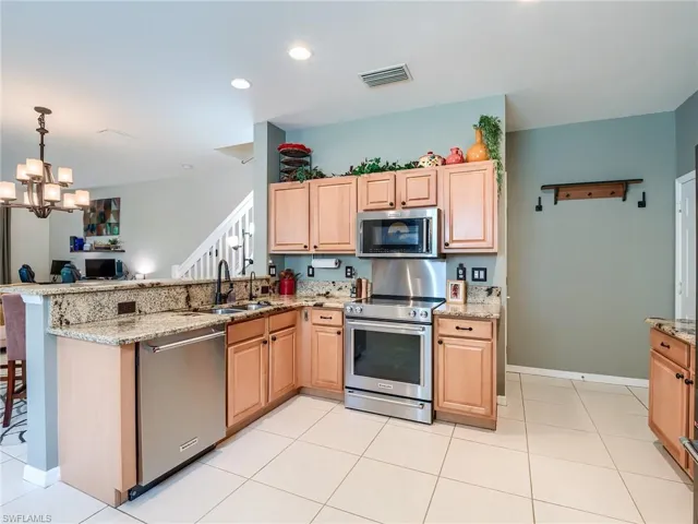 Kitchen with kitchen peninsula, sink, light tile patterned floors, and stainless steel appliances