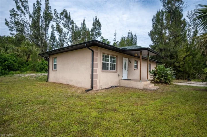 View of side of home with stucco siding, a patio area, and a lawn