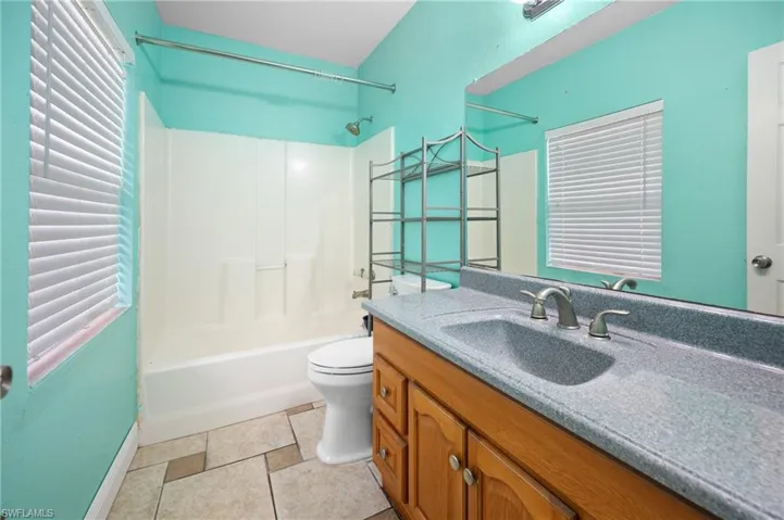 Primary Bathroom with toilet, vanity, and shower / washtub combination
