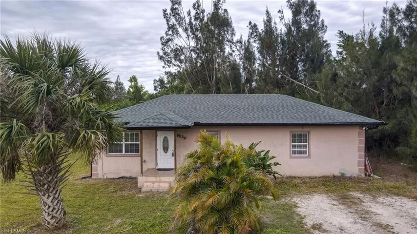 View of front of house with a shingled roof, a front yard, and stucco siding