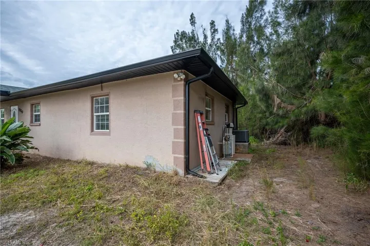 View of side of home with central AC and stucco siding