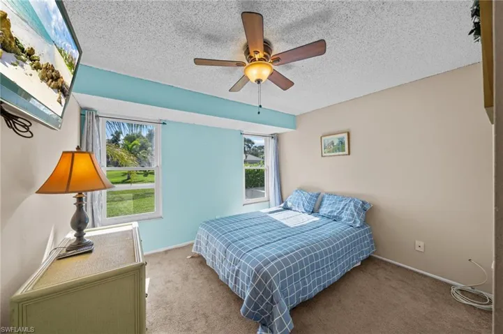 Carpeted bedroom with a ceiling fan and a textured ceiling