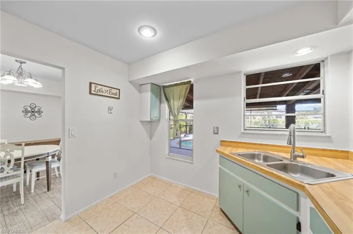 Kitchen featuring light countertops, green cabinetry, light tile patterned floors, and a chandelier