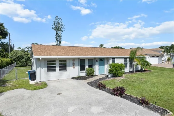 Ranch-style home featuring a shingled roof and driveway