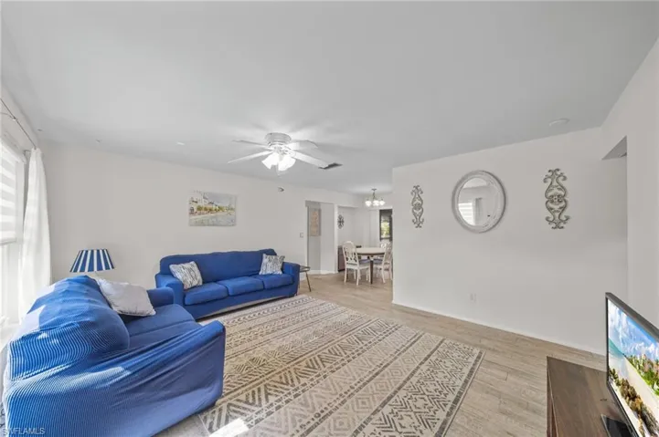 Living room featuring light wood-style flooring, ceiling fan, and a chandelier