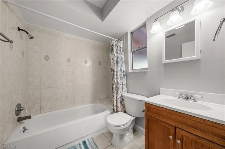 Bathroom with shower / bath combination with curtain, light tile patterned flooring, and vanity