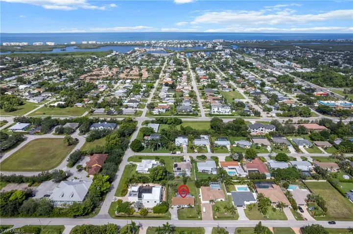 Aerial view of property and surrounding area featuring nearby suburban area and a large body of water
