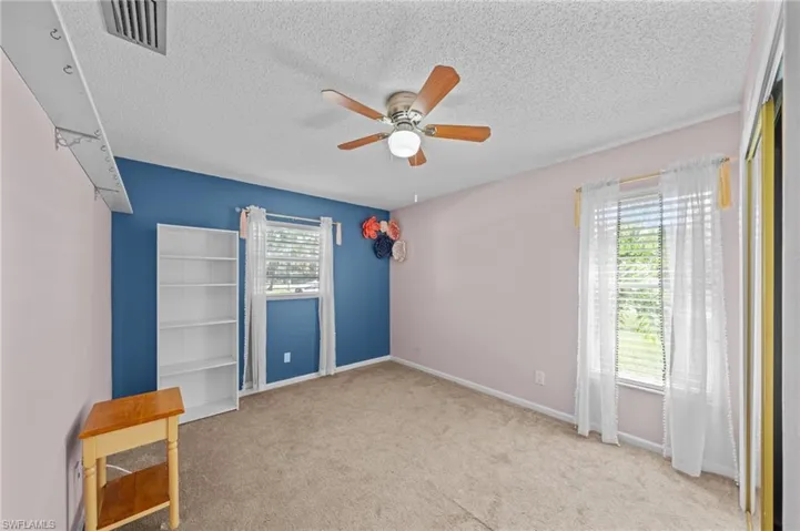 Unfurnished room featuring light colored carpet, a textured ceiling, and a ceiling fan